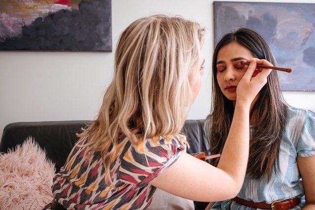 A beauty consultant applying make up to a lady